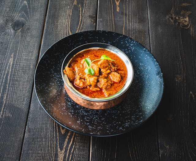 Bowl of mutton curry on a plate